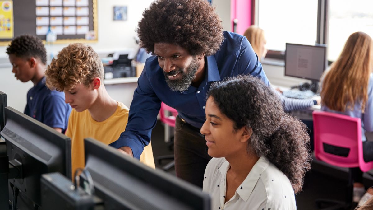 STEM teacher working with high school students on computers