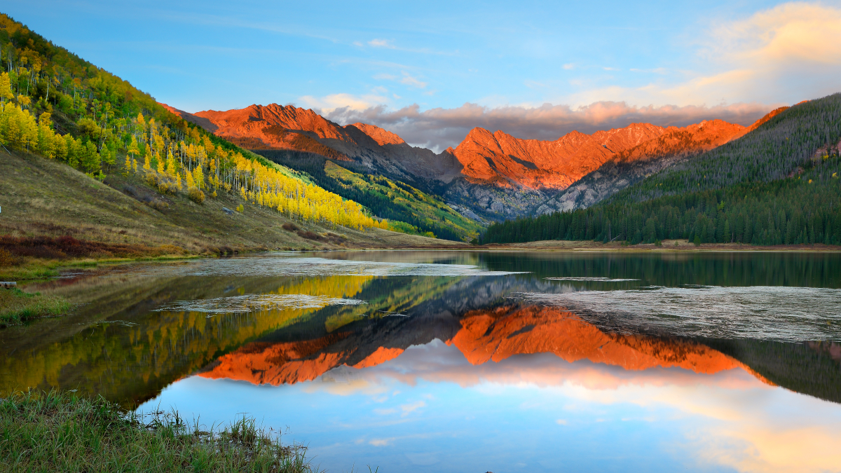 orange mountains at sunset reflecting on lake 