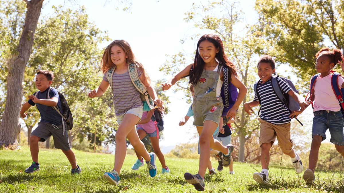 Multi-ethnic group of schoolchildren running in the park