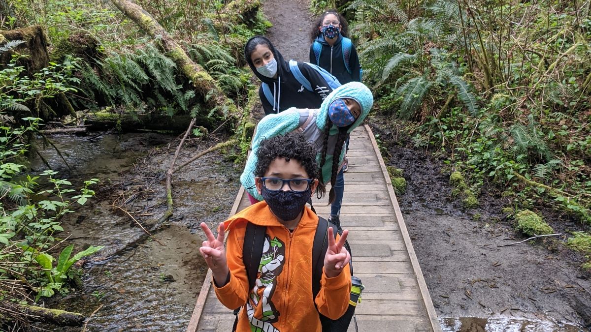 A line of students on a wooden walkway that crosses over a creek