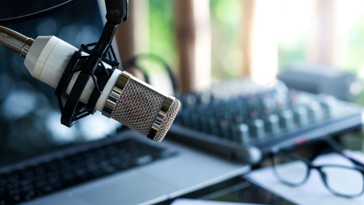 Close-up of a microphone and in the background is a laptop that's slightly blurry
