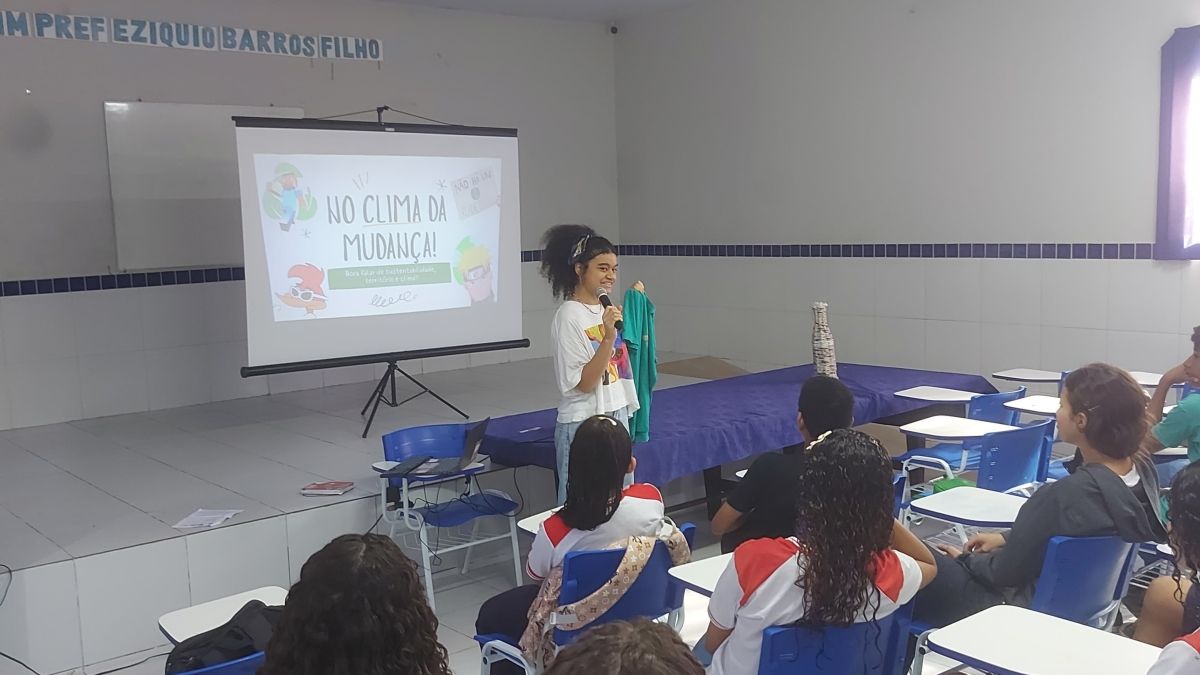 A young woman speaking in front of high school students