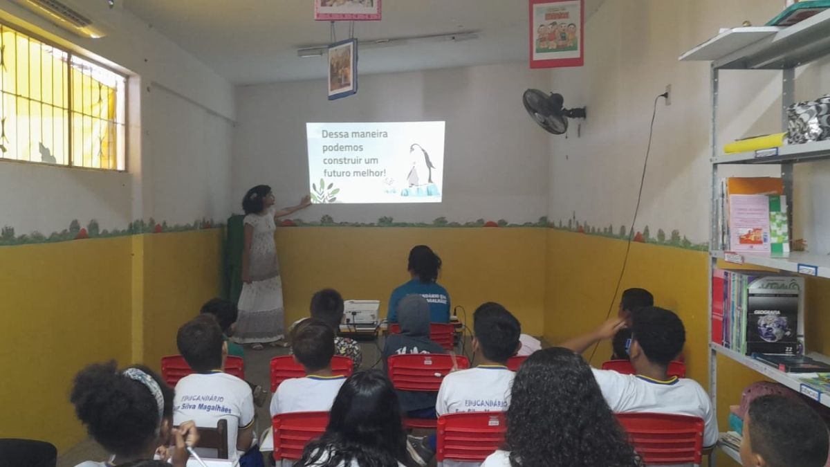 A young woman speaking in front of an elementary school classroom