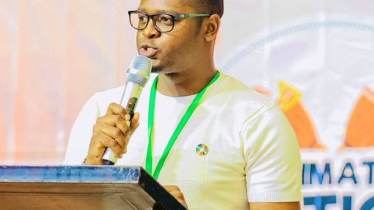 A young man in a yellow t-shirt speaking at a podium