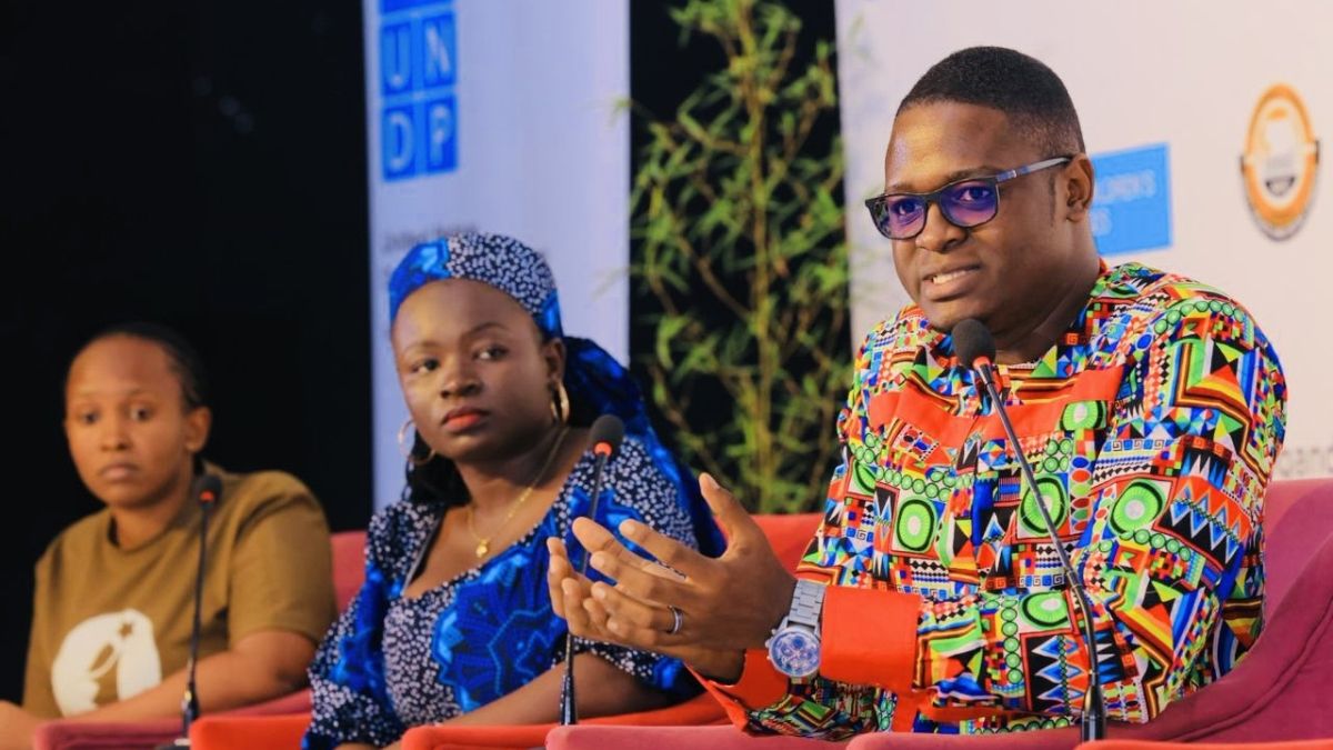 Three people speaking on stage on a panel