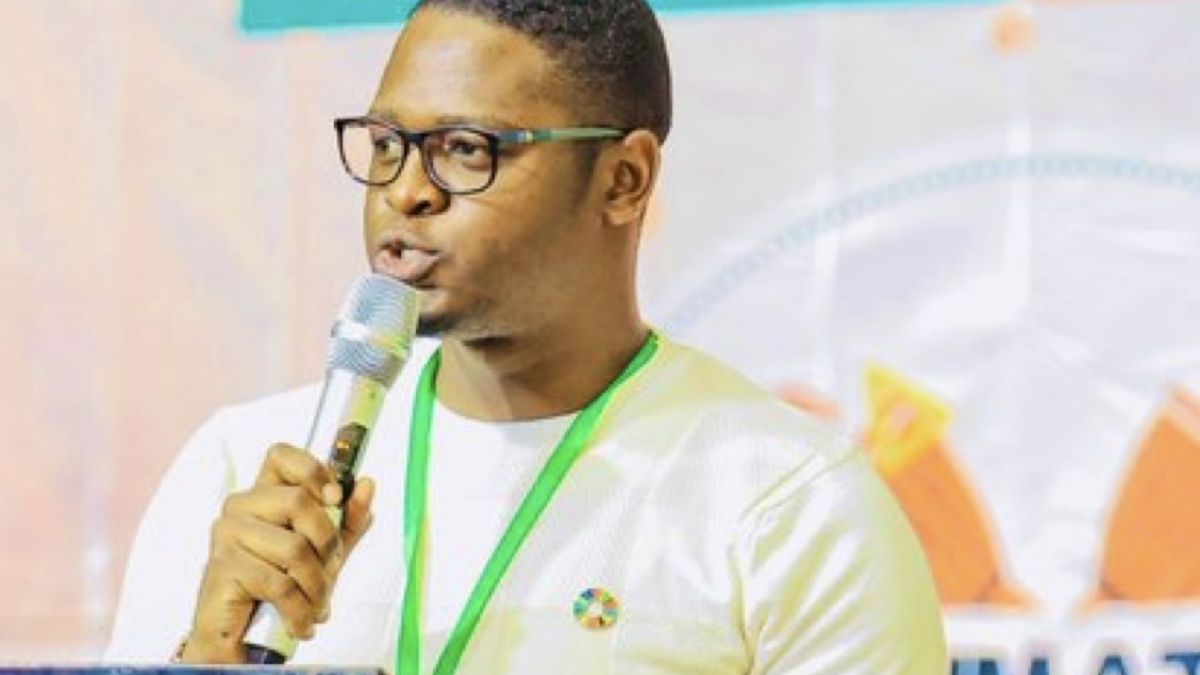 A young man in a yellow t-shirt speaking at a podium