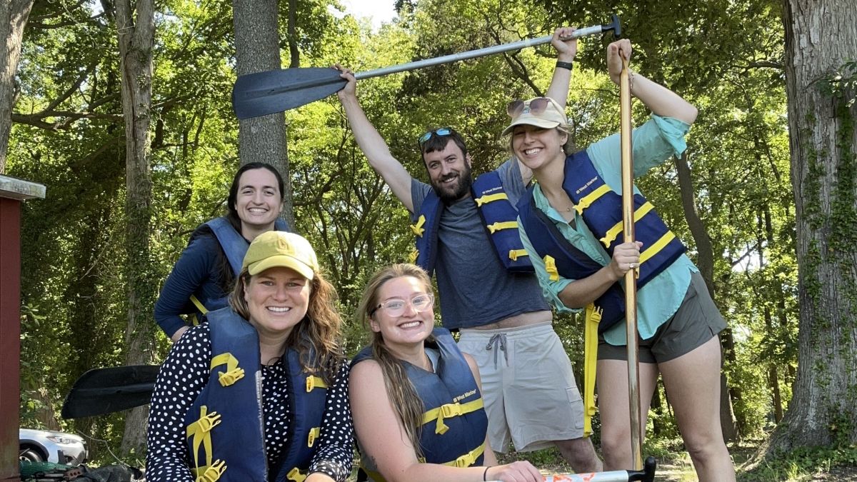 Adults posing with paddles and life jackets
