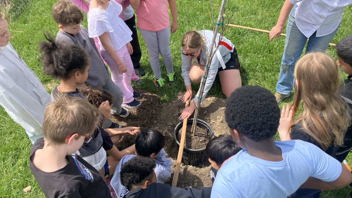 Morgan demonstrating tree planting to young people