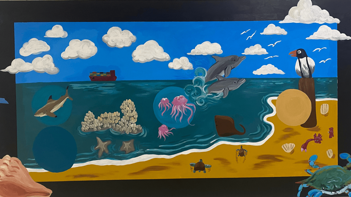 a school hallway mural depicting the beach and near-ocean animals, including dolphins, jellyfish, coral, crabs, and seashells.