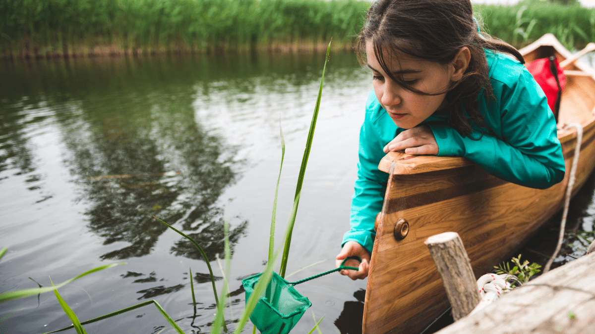 Student in a canoe taking a water sample