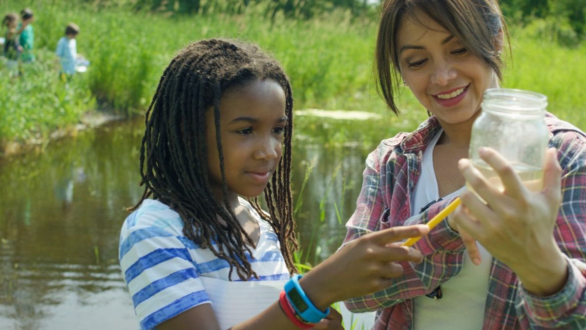 Student and teacher examine jar of water