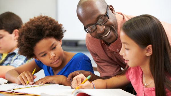 young students working with teacher in classroom