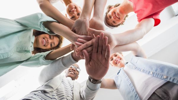 image from below group of people in circle touching hands