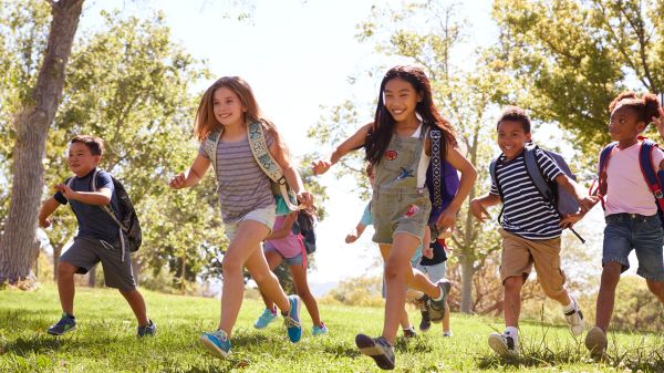 Multi-ethnic group of schoolchildren running in the park