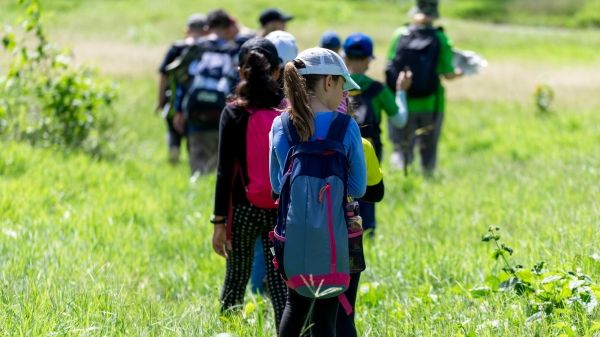 A group of people hike in a green field.
