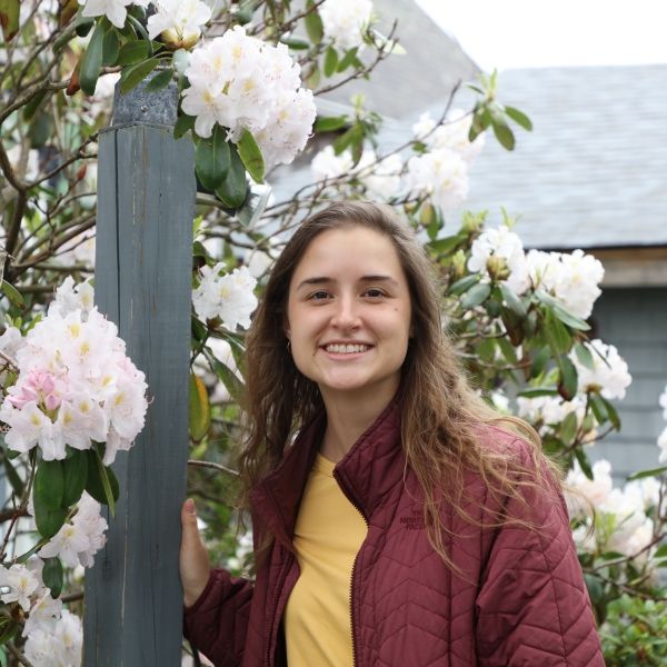Headshot of Alex in front of blooming flowers