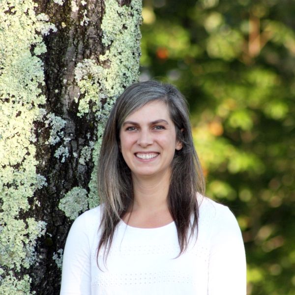Woman in white shirt standing in front of a tree