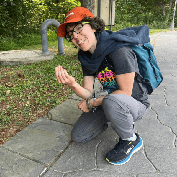 Darien crouching on the ground with an insect