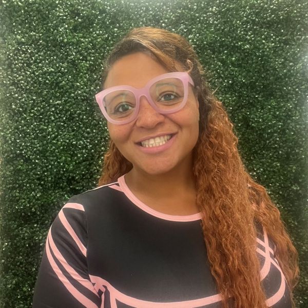 Monica outside in front of a green wall