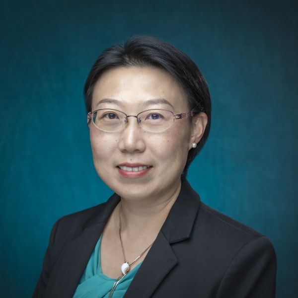 Christine in a black suit jacket with a blue background