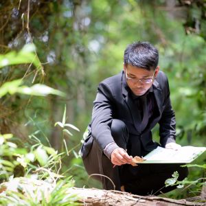 man in forest studying plants