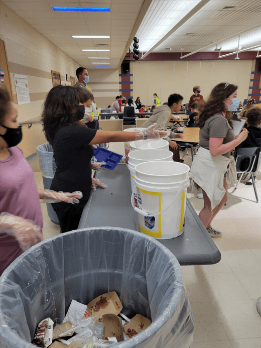 Students wearing gloves are conducting a school activity with four buckets on a table