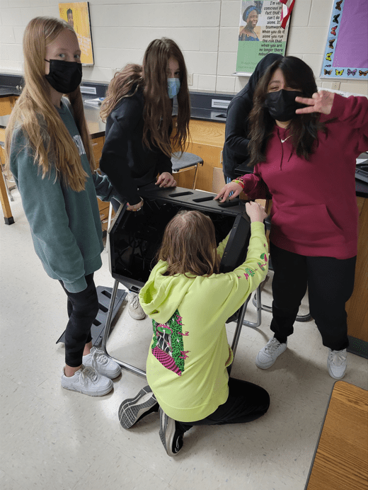 Four students in a classroom, building a composting bin.
