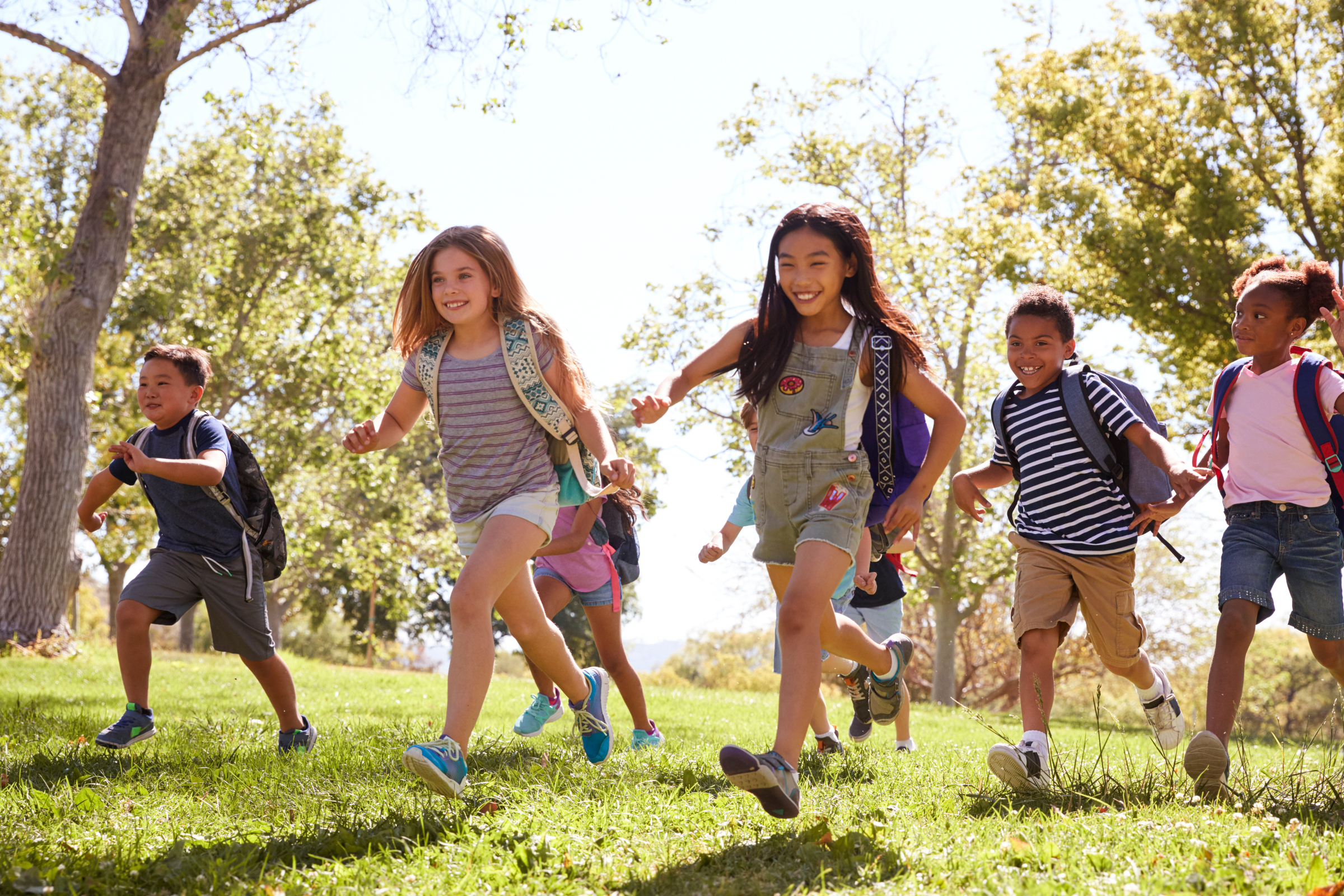 Multi-ethnic group of schoolchildren running in the park