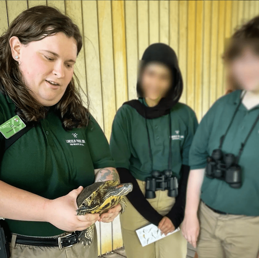 CJ holding a red-eared slider turtle teaching students about pond ecology.