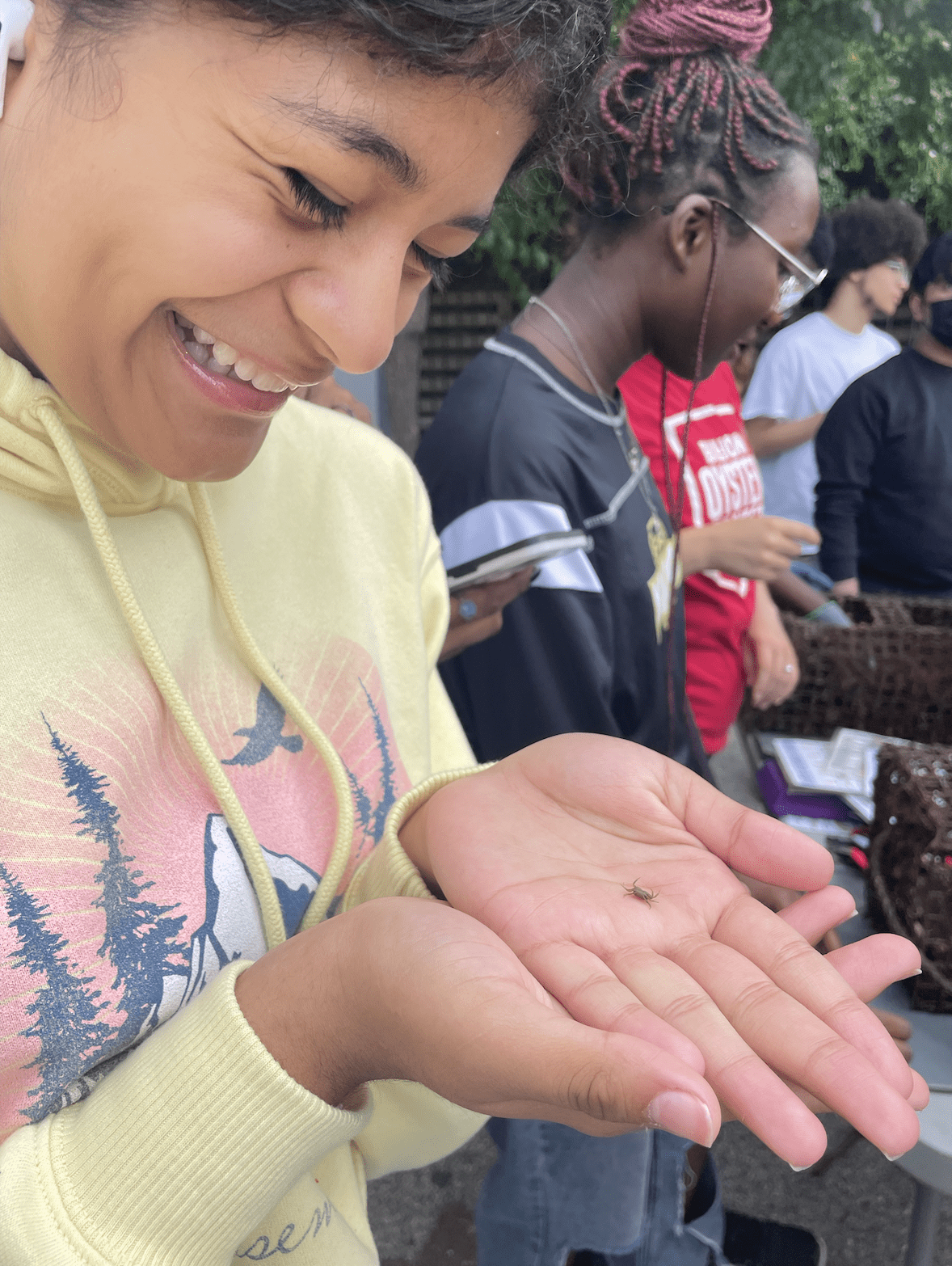 A student participant joyfully holding a tiny crab at her local marina's oyster restoration reef on a class field trip led by Start:Empowerment and in partnership with the Billion Oyster Project.