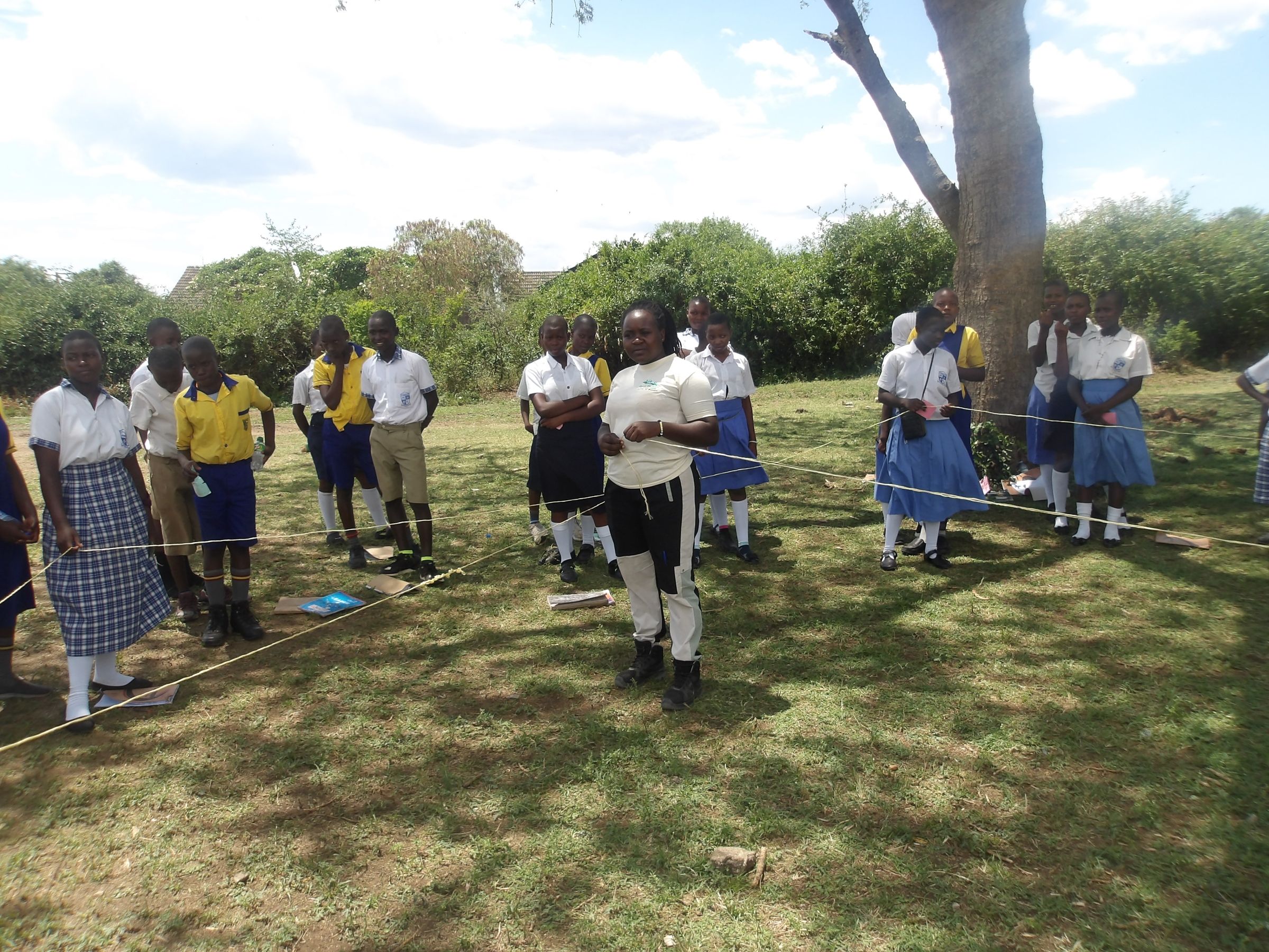 An adult leading a demonstration with students outside using string