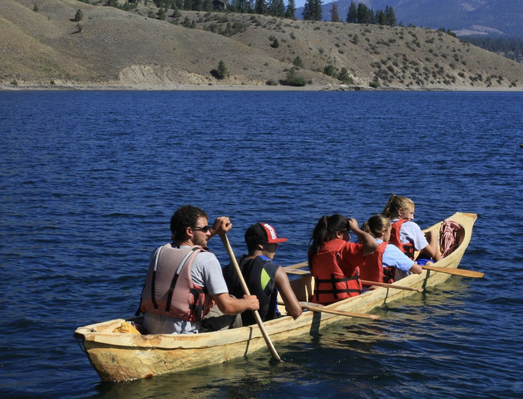 A group of people paddling in a dugout canoe on water