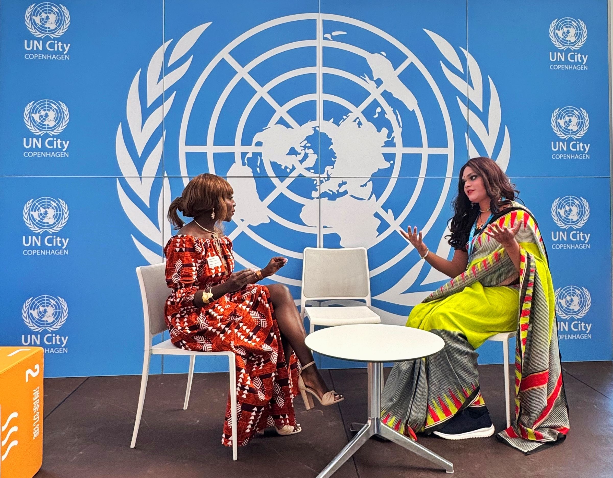 Two women having a conversation with the UN logo in the background.