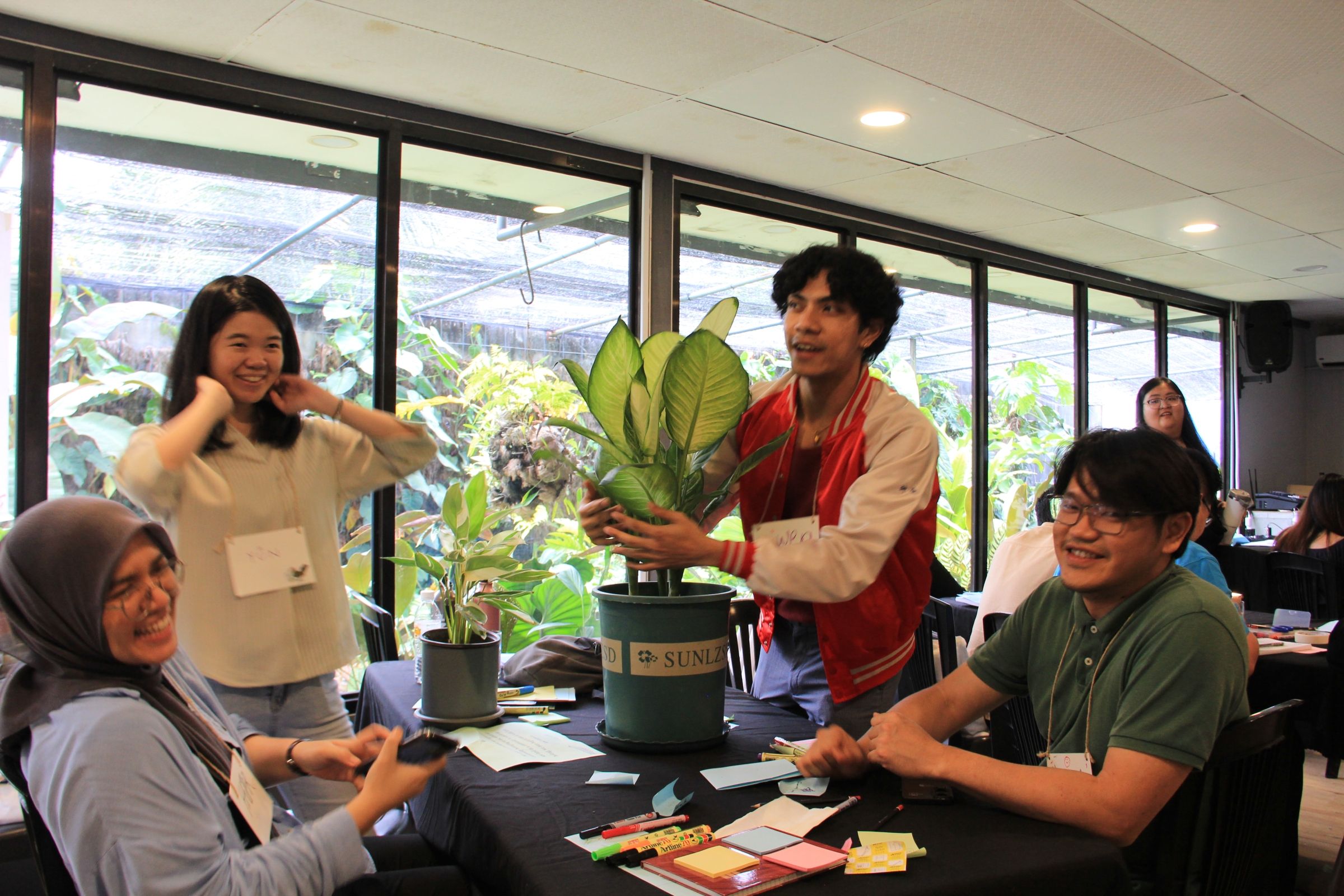 A small group of young people holding a large plant.