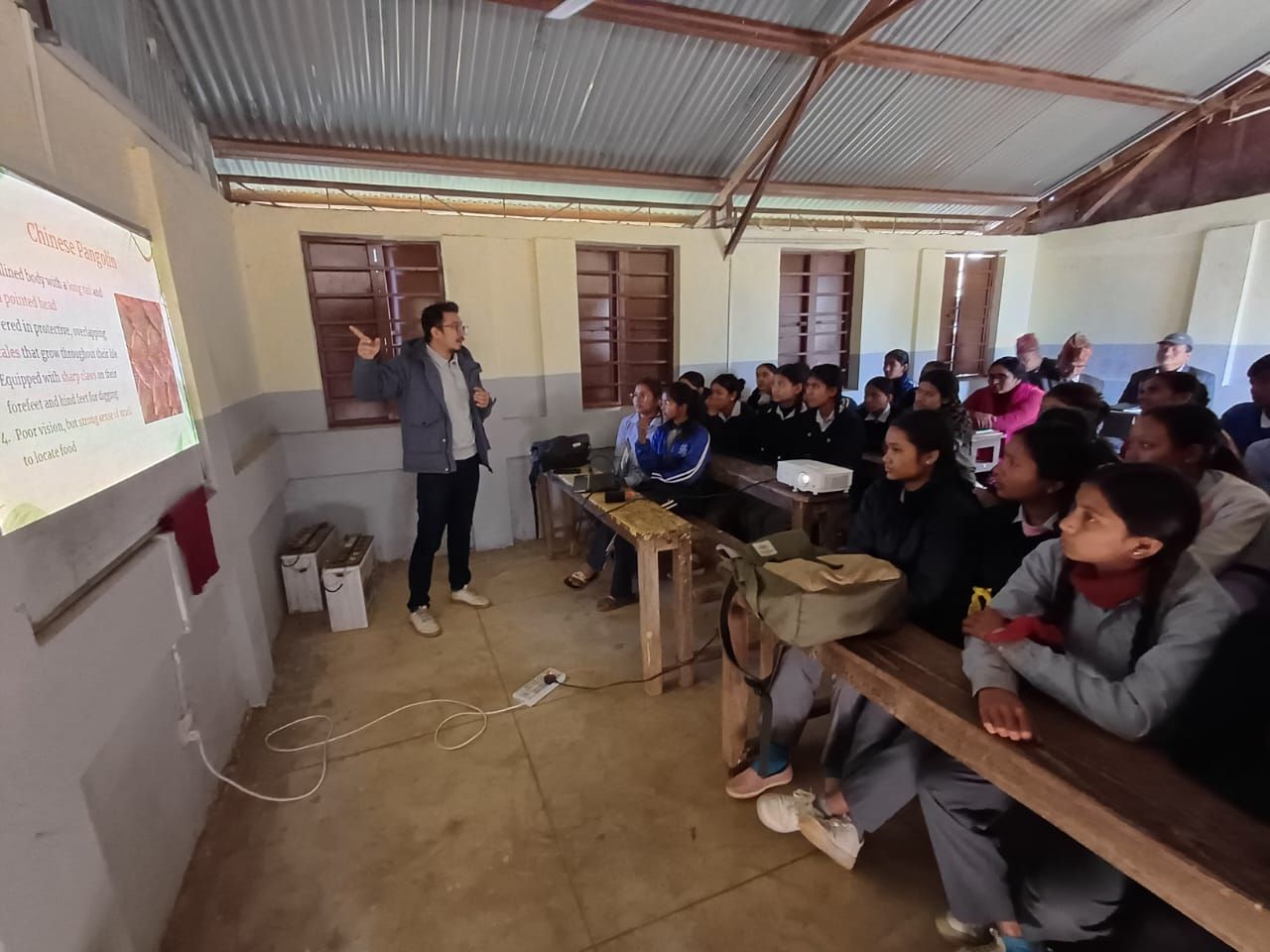 A man teaching at the front of class of students.