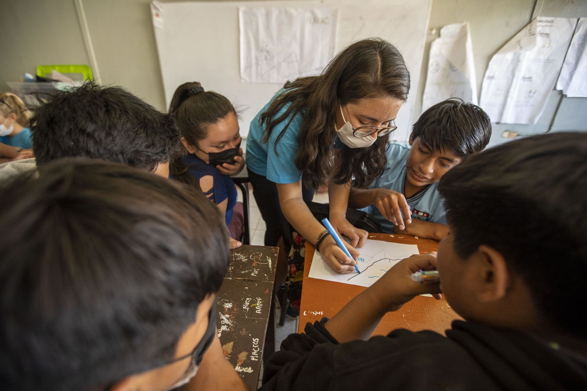 A woman works closely with students on a project.