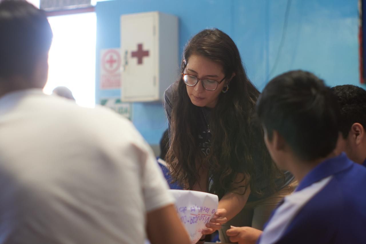 A woman working closely with a group of students.