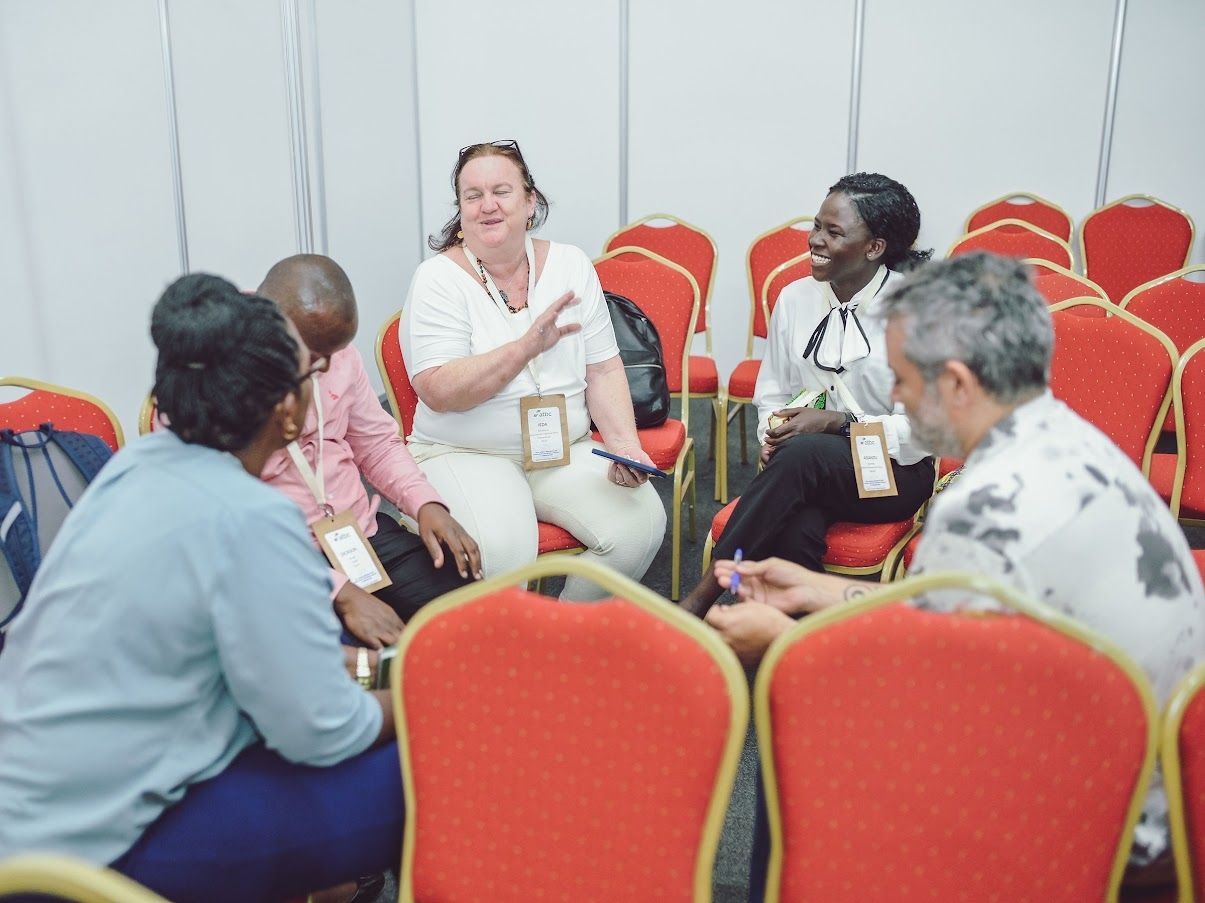 Adults smiling and talking together in a seated circle