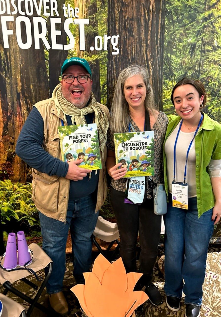 Three people standing and holding "Discover the Forest" materials
