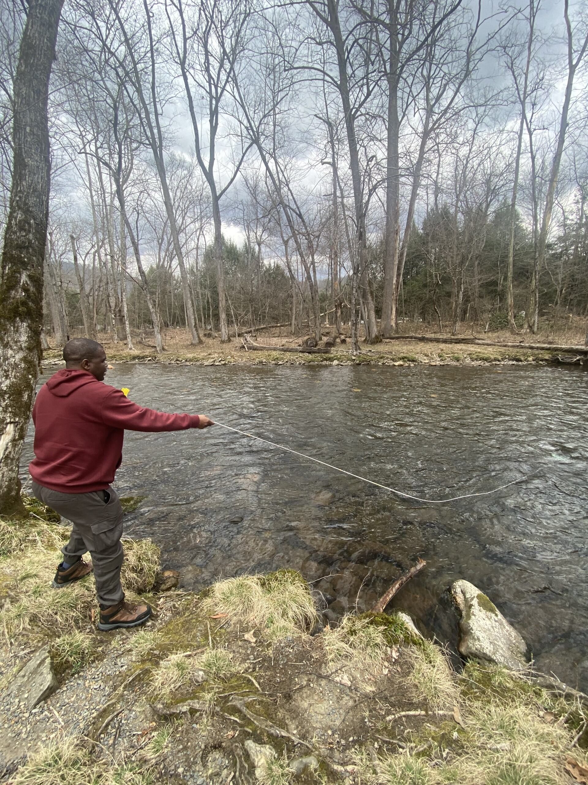 Kgosi pulling on a rope at the edge of a river