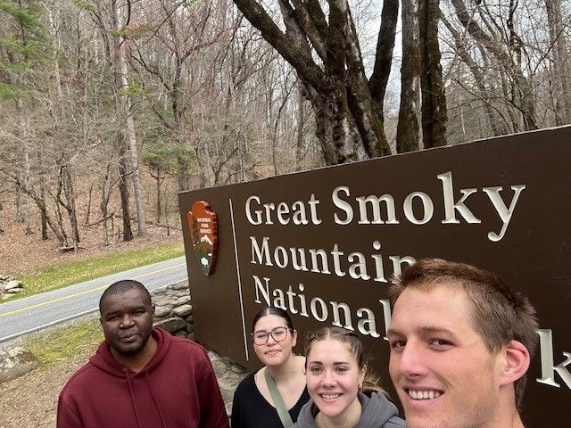 Kgosi and students posing in front of a sign for the Great Smoky Mountains National Park