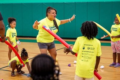 Students in yellow shirts playing with red and yellow foam noodles