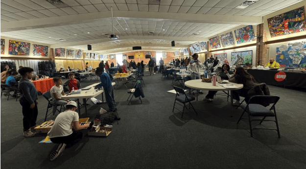 Students organized at tables in a large colorful room