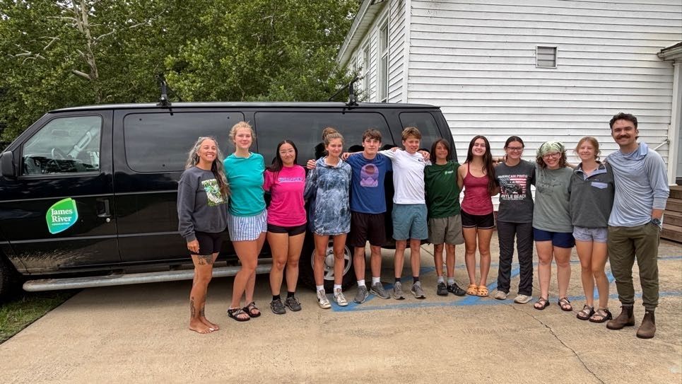 Teresa and students posing in front of a van