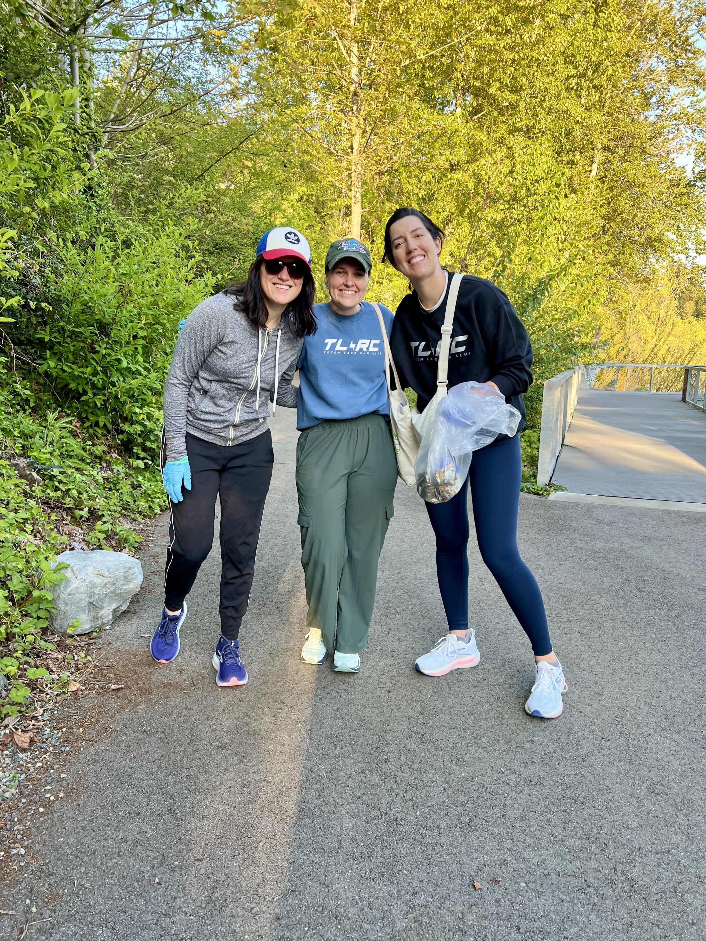 Bethany and two other adults pose for a photo while holding waste collection bags