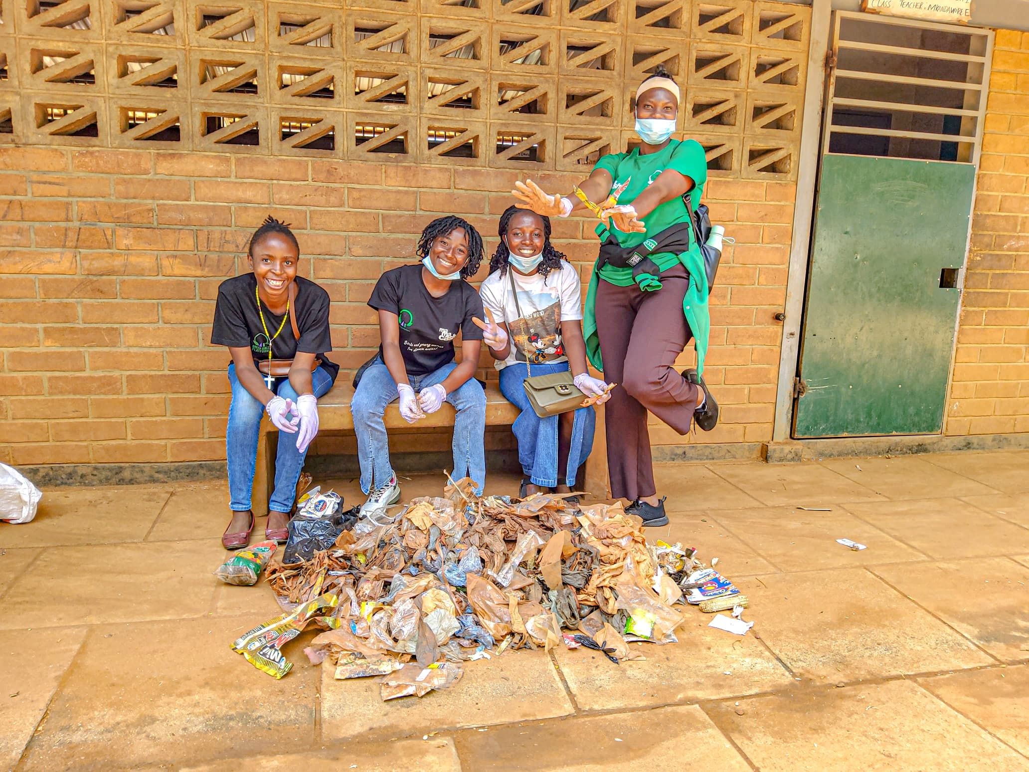 Four young people pose next to a pile of collected litter
