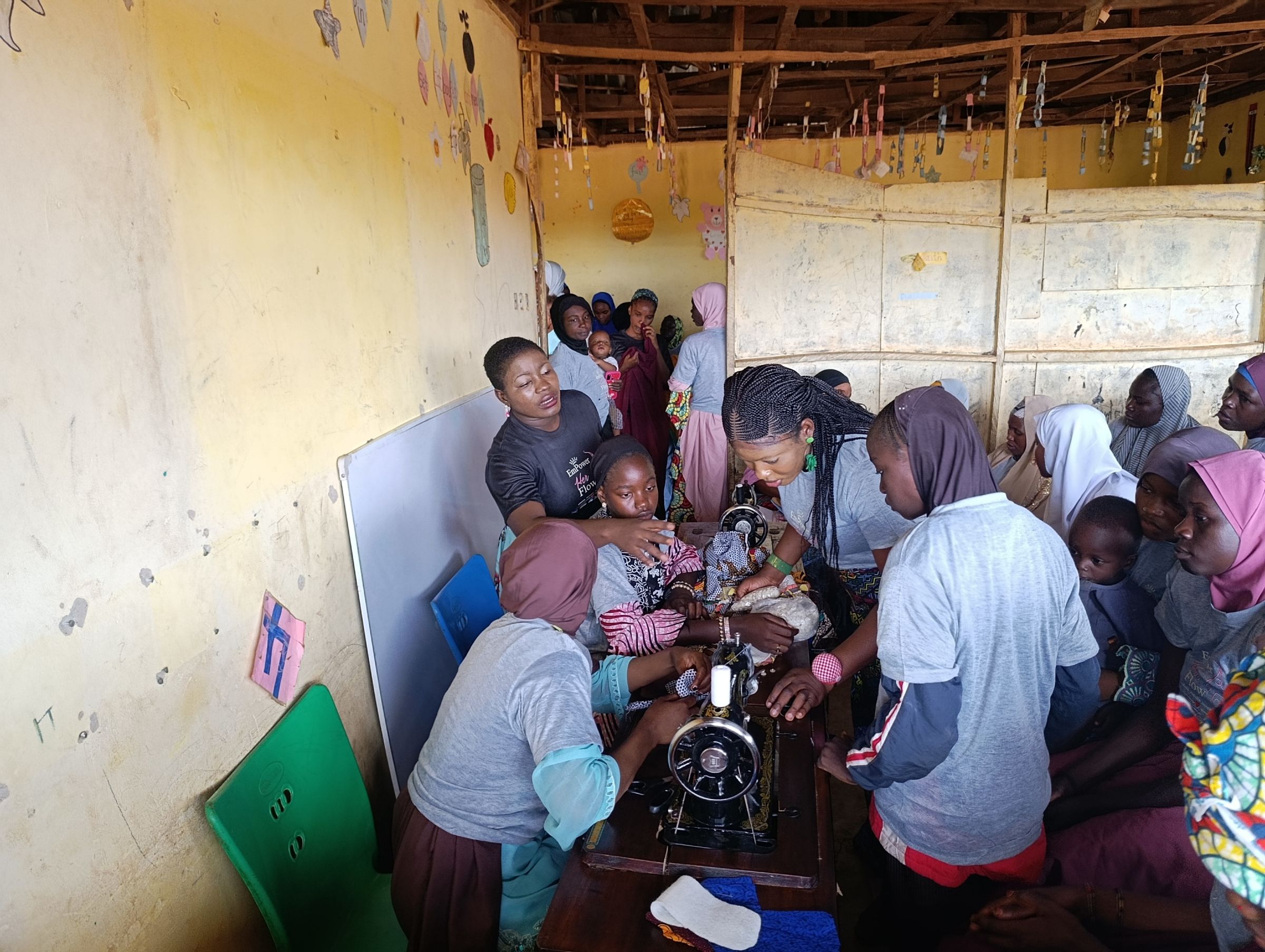 A group of women surround a sewing machine during a lesson