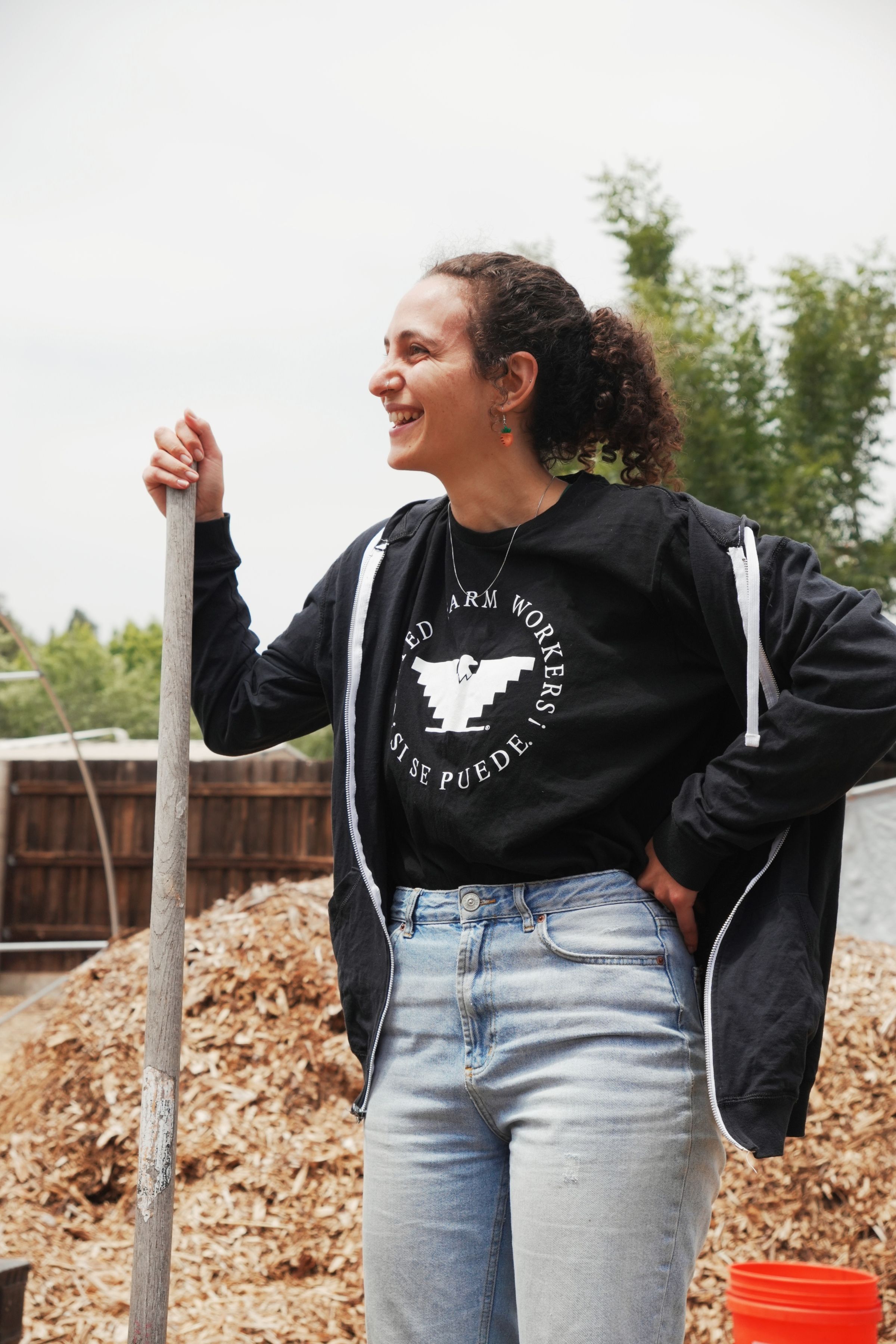 Zoë turns a compost pile on a field trip with high school students to a local urban farm